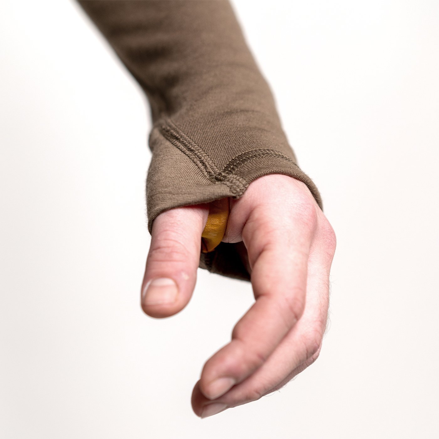 A person wears a Hillman 2BL Merino Wool Base Layer-Hunting Long Sleeve Thermal T-shirt with a thumbhole on the brown sleeve, exposing their thumb against a plain white background.